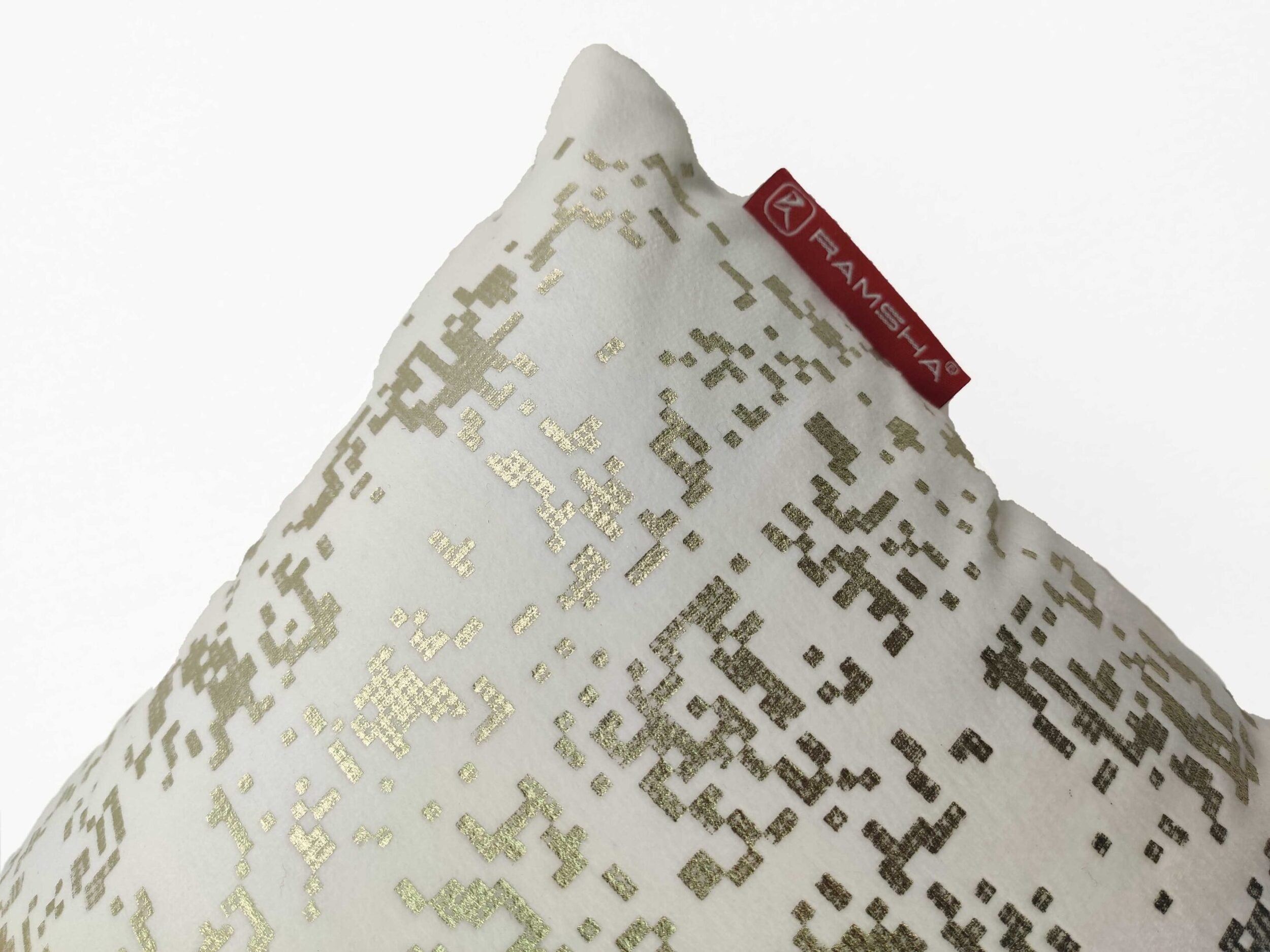 A close-up of the White Cushion CS-097 by RAMSHA HOME showcases its gold pixelated pattern and red tag, blending style and comfort with a high-density filler.