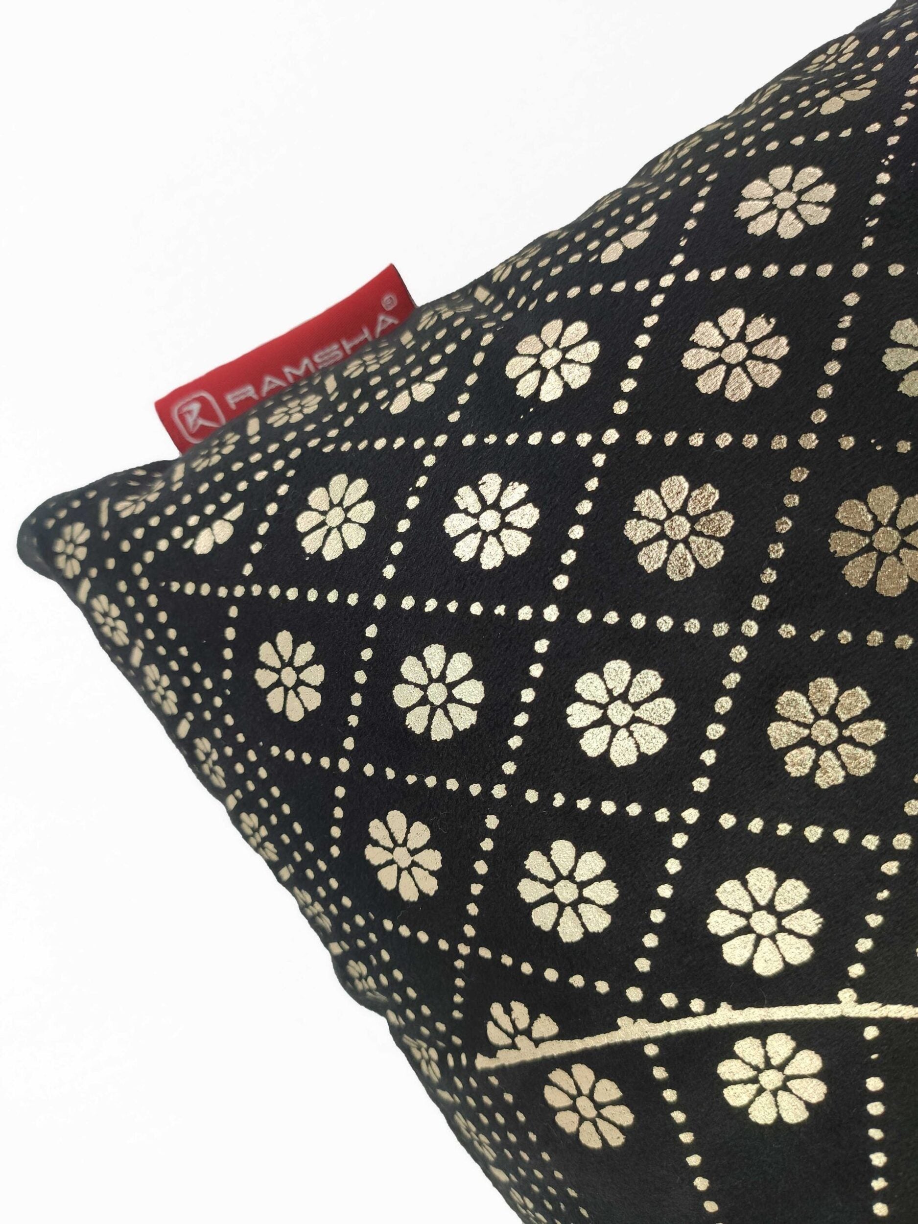 A close-up of the Home Decor Polyester Cushion in black, featuring a gold floral and dotted geometric pattern with a red RAMSHA HOME fabric tag—perfect for adding stylish flair to your space.