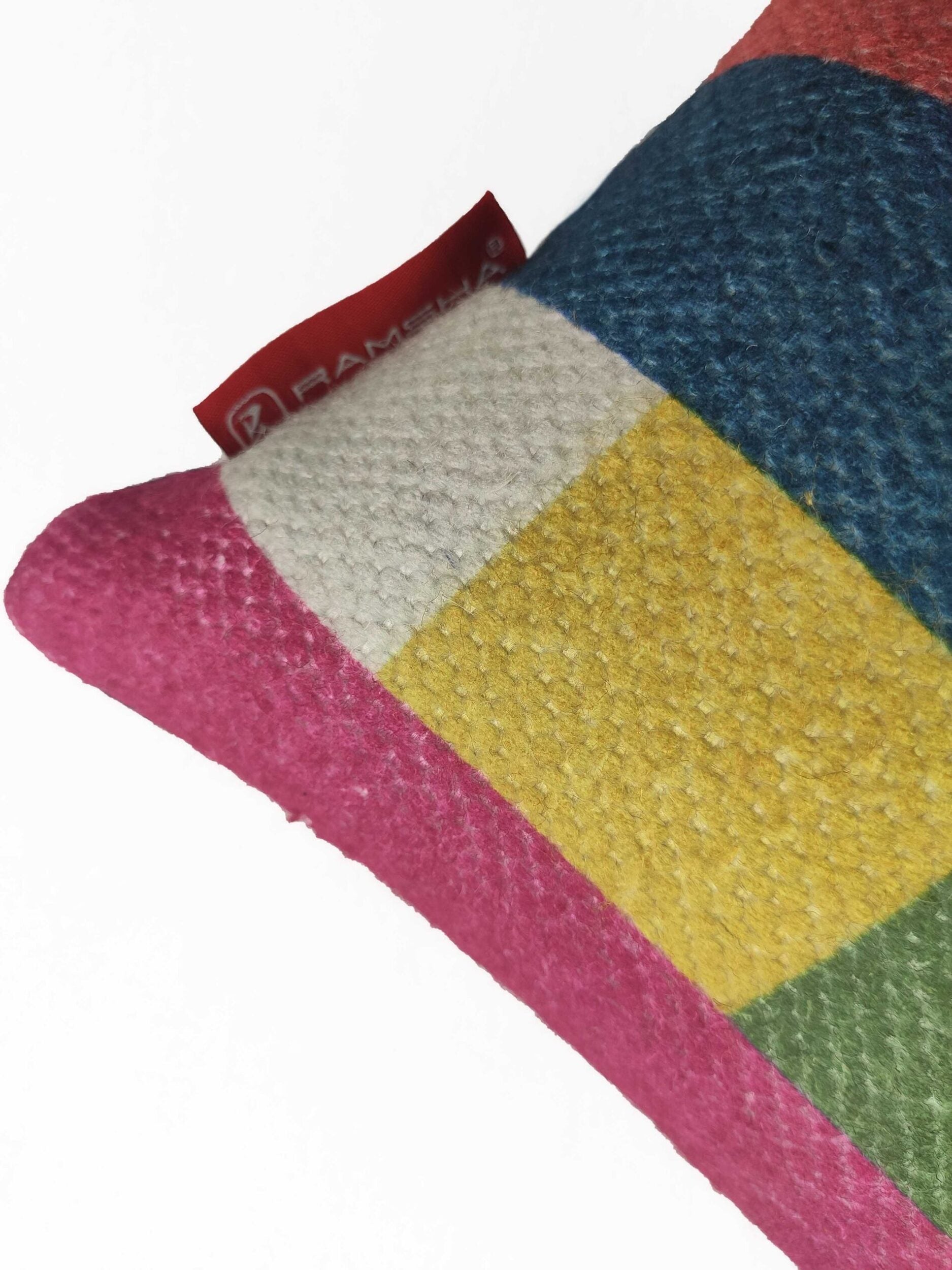 A close-up of the RAMSHA HOME Home Decorative Cushion With Filler CS-071, showcasing textured pink, white, yellow, blue, and green sections with a small red fabric tag on the upper left edge.