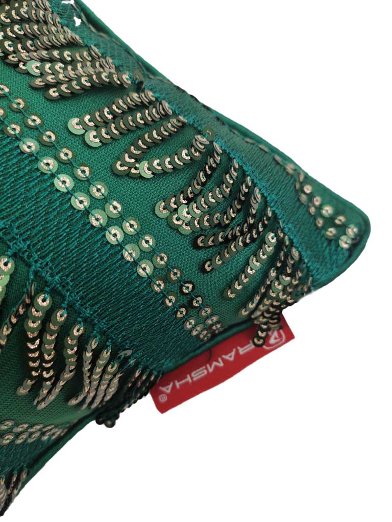 A close-up of RAMSHA HOME's Polyester Sequence Cushion With Filler shows its green fabric with gold leaf-pattern sequins, plus a red tag with white text at the bottom edge, highlighting its comfortable support.