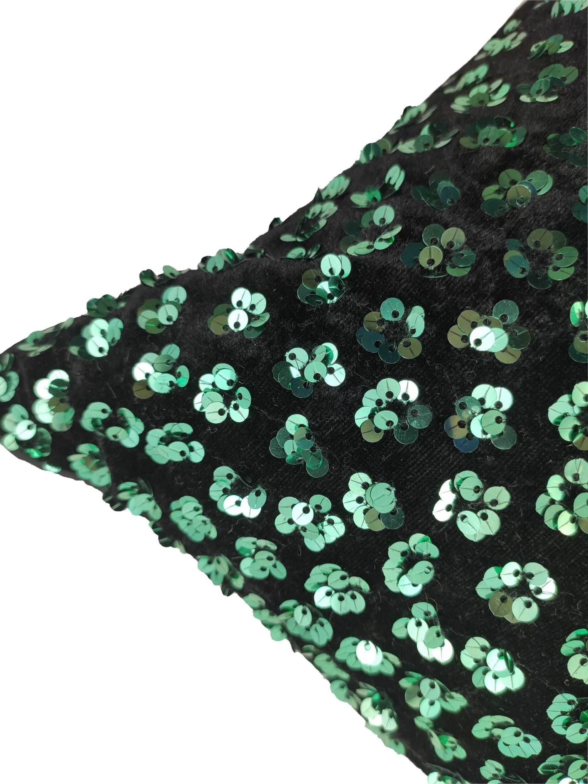 Close-up of the RAMSHA HOME Polyester Cushion With Filler shows its black polyester fabric adorned with shiny green sequins, creating a shimmering effect against a white background for stylish and comfortable seating.