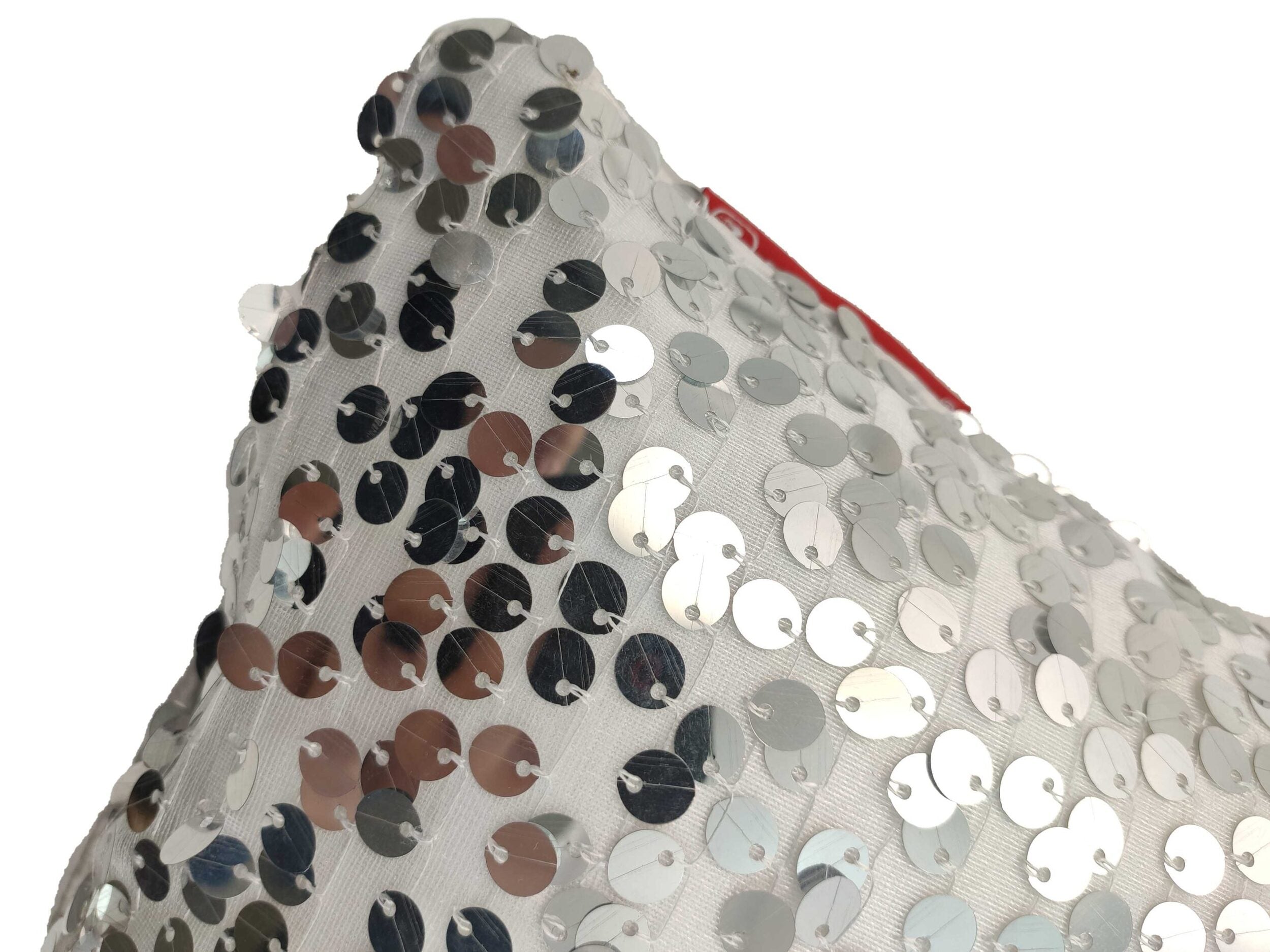 Close-up of the RAMSHA HOME Sequence Cushion With Filler, featuring a white cover adorned with shiny silver sequins for a sparkling look. A hint of red tag at the top suggests the plush comfort of the included filler.