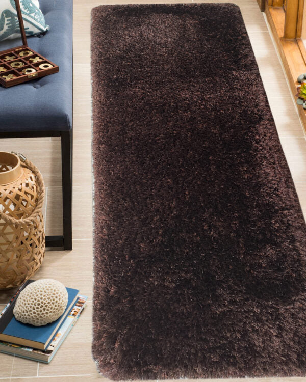 The RAMSHA HOME Fluffy Brown Color Dining Room Shaggy Rug - MPV 04 (60x180cm) lies on a light tile floor next to a blue cushioned bench, a woven basket, and books with a white textured ball on top.