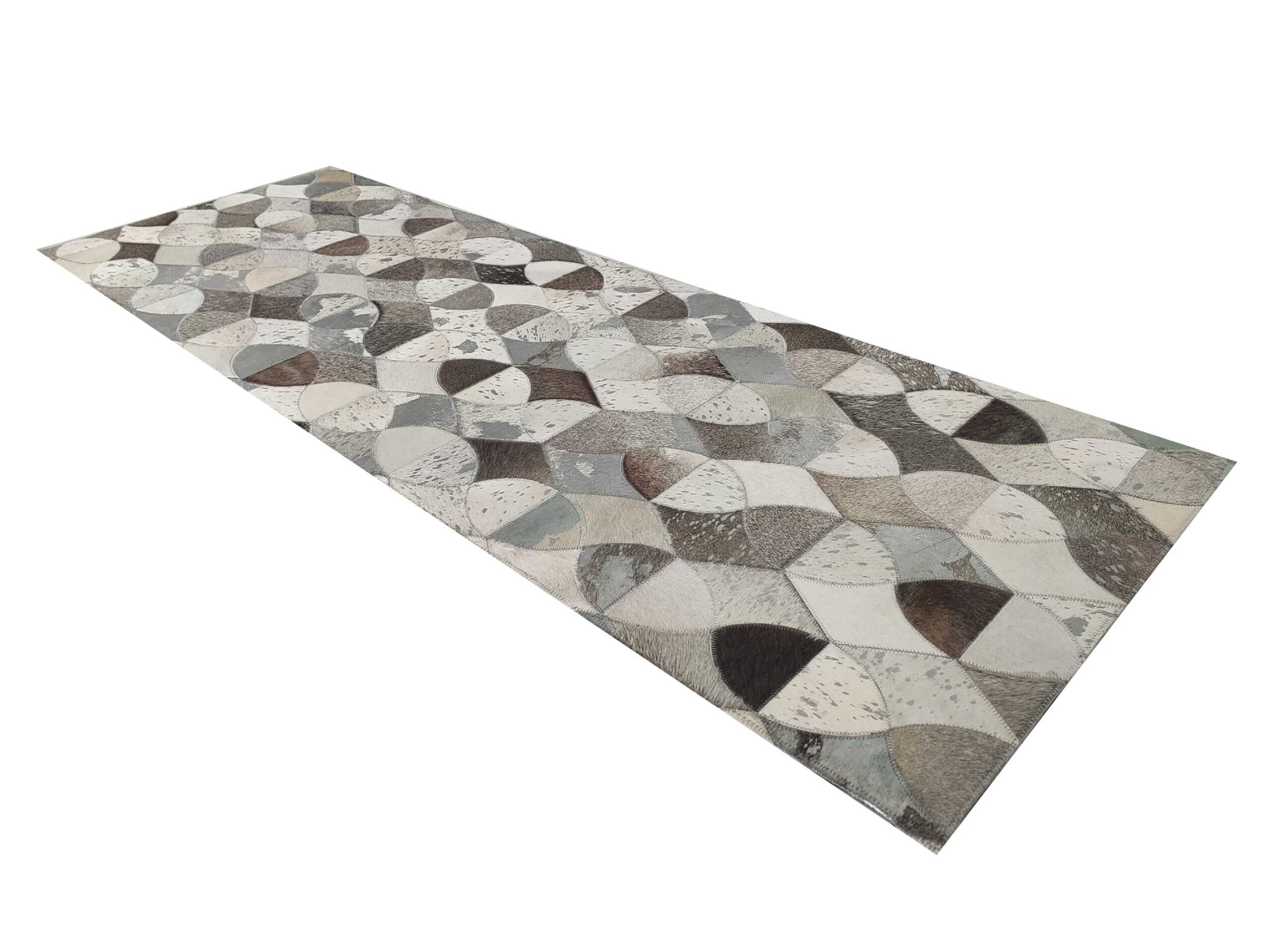 The Delightful Modern Grey Color Leather Rug - LR 008 by RAMSHA HOME features a rectangular shape with a leaf pattern in gray, white, and beige, shown at an angle to emphasize its length and repeating design.
