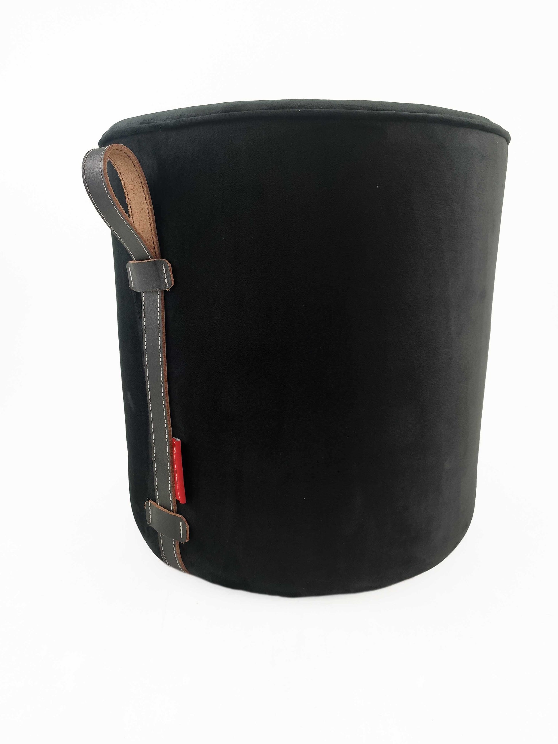 The RAMSHA HOME Leather Pedestal Pouf With Leather Handle is a round black velvet leather pouf with a brown handle, white stitching, and a small red accent tag, shown against a plain white background.