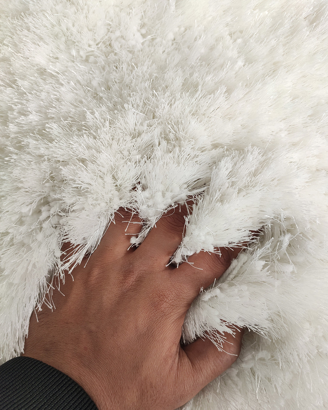 A hand gently presses into the thick, fluffy fibers of the RAMSHA HOME White Color Entryway Decor Shaggy Rug - MPV 01 (250x350cm), partially burying fingers in its plush ivory surface.
