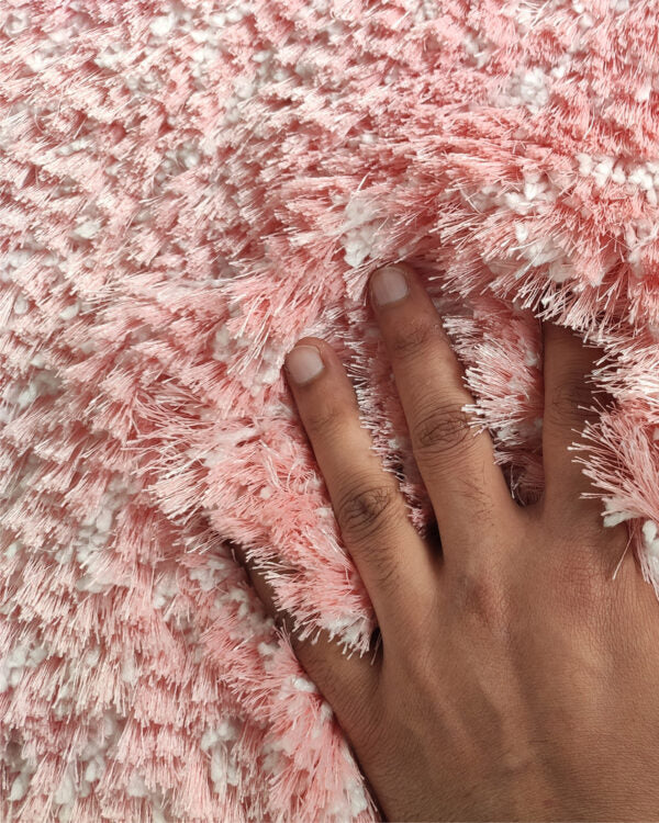 A hand with neatly trimmed nails presses into the Pink Color Modern Kids Room Decor Shaggy Rug - MPV 06 (200x300cm) by RAMSHA HOME, creating visible indentations among the soft and cozy pink and white fibers.
