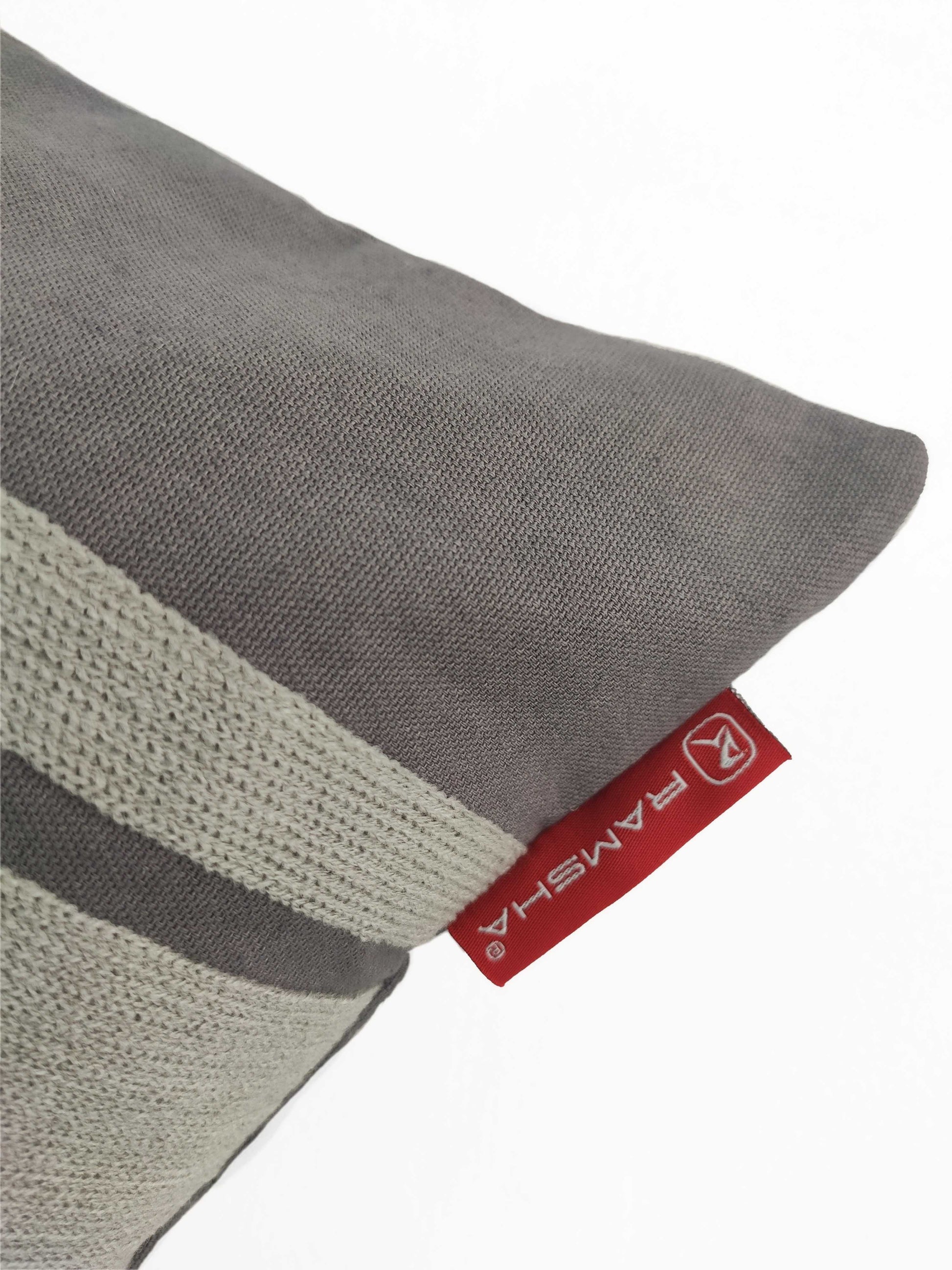 A close-up of the Grey Color Cushion CS-119 by RAMSHA HOME, made from a soft cotton-polyester blend with off-white stripes and a red tag bearing the RAMSHA logo. The background is plain white.