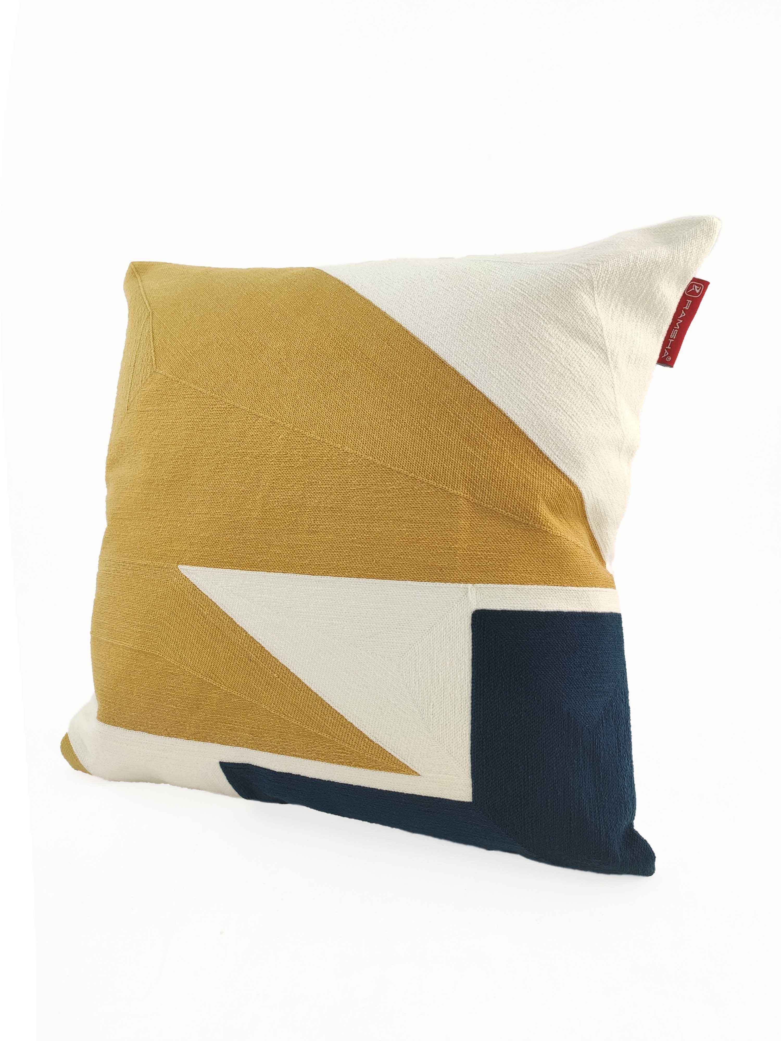 The RAMSHA HOME Home Decor Cushion CS-120 features a modern geometric design in mustard yellow, white, and dark blue on a square cotton-polyester cover with a small red fabric tag for stylish, durable home decor.