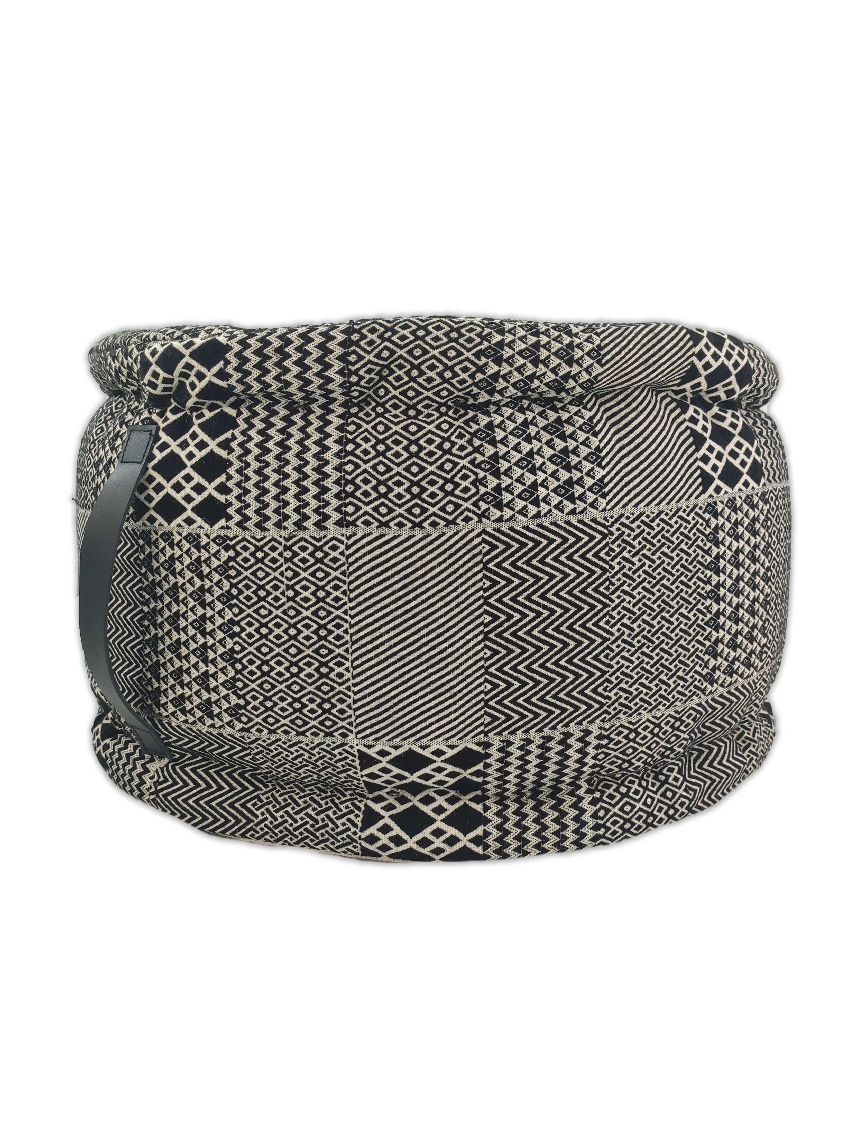 The RAMSHA HOME Black And White Pouf With Leather Handle PF-040 features a round fabric design with bold geometric patterns, including zigzags and diamonds, on a white background—ideal for adding stylish flair to your home decor.