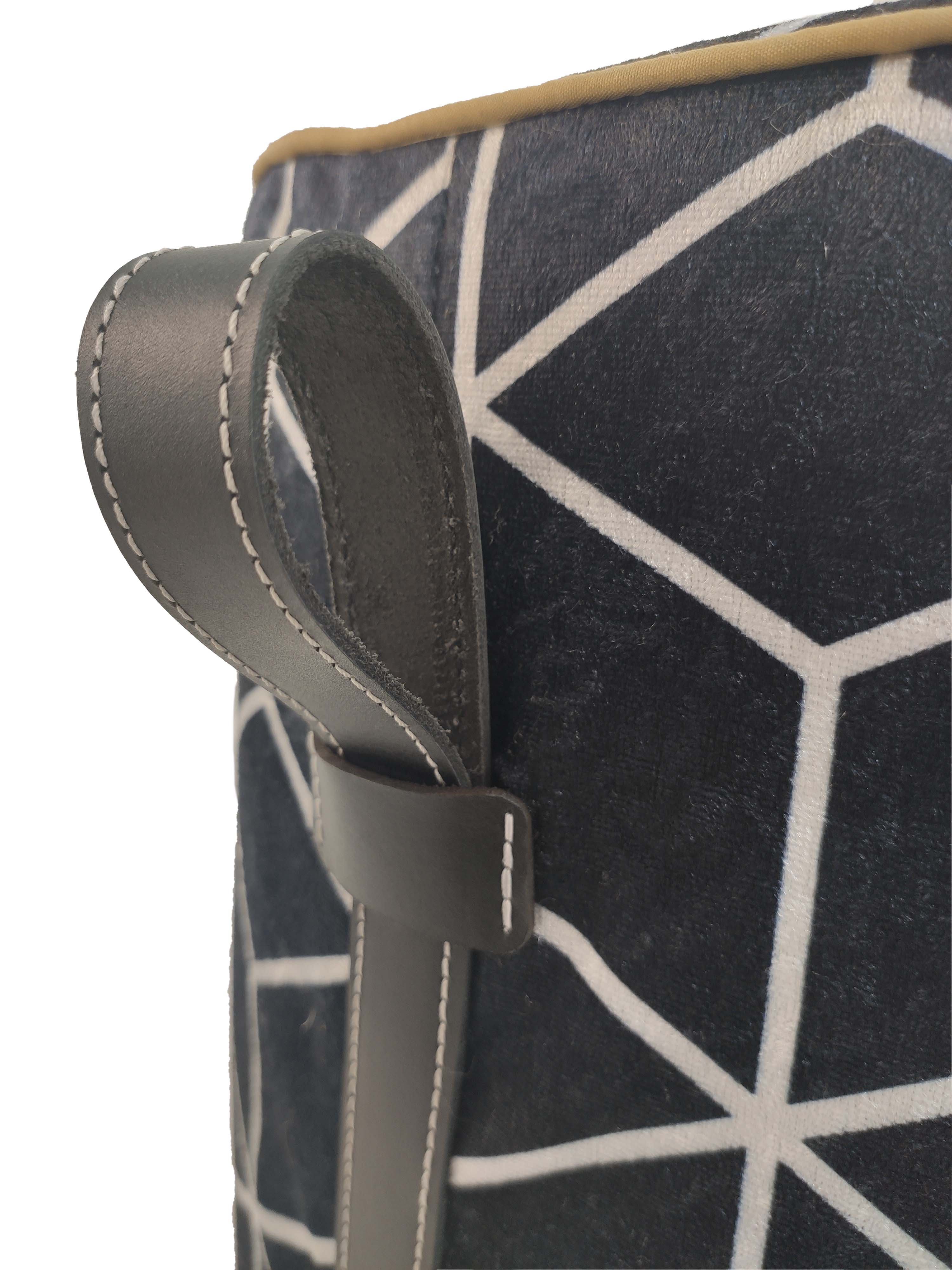 The RAMSHA HOME Printed Pedestal Pouf With Leather Handle PF-028 features a dark fabric with a white geometric print, a stitched gray leather handle on the side, and tan trim—adding modern charm as a stylish accent to your home.