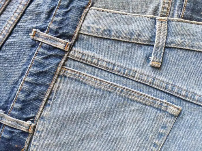 Close-up of overlapping blue denim jeans, highlighting back pockets and stitching—capturing the textured look of the Ramsha Home Multi Color Cotton Denim Rug – DN 001 in various blue shades.