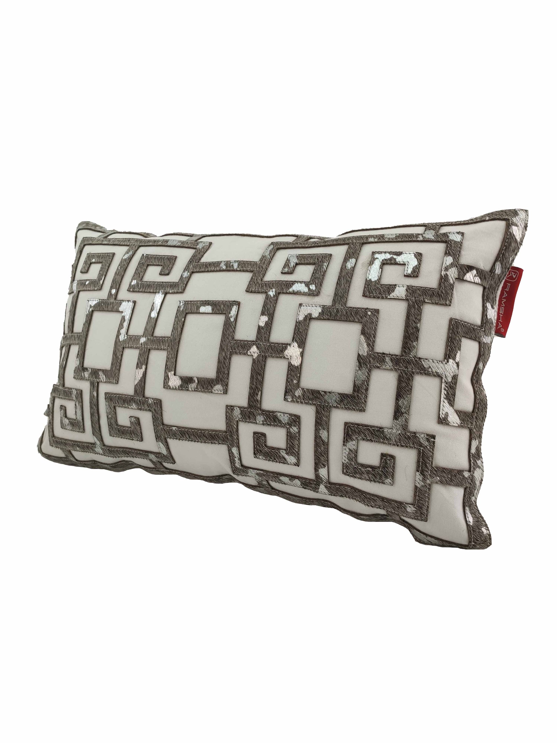 The RAMSHA HOME Modern Cushion CS-107 is a rectangular cushion with a metallic silver and white Greek key pattern, sequins, embroidered details, and a small red tag on one side.