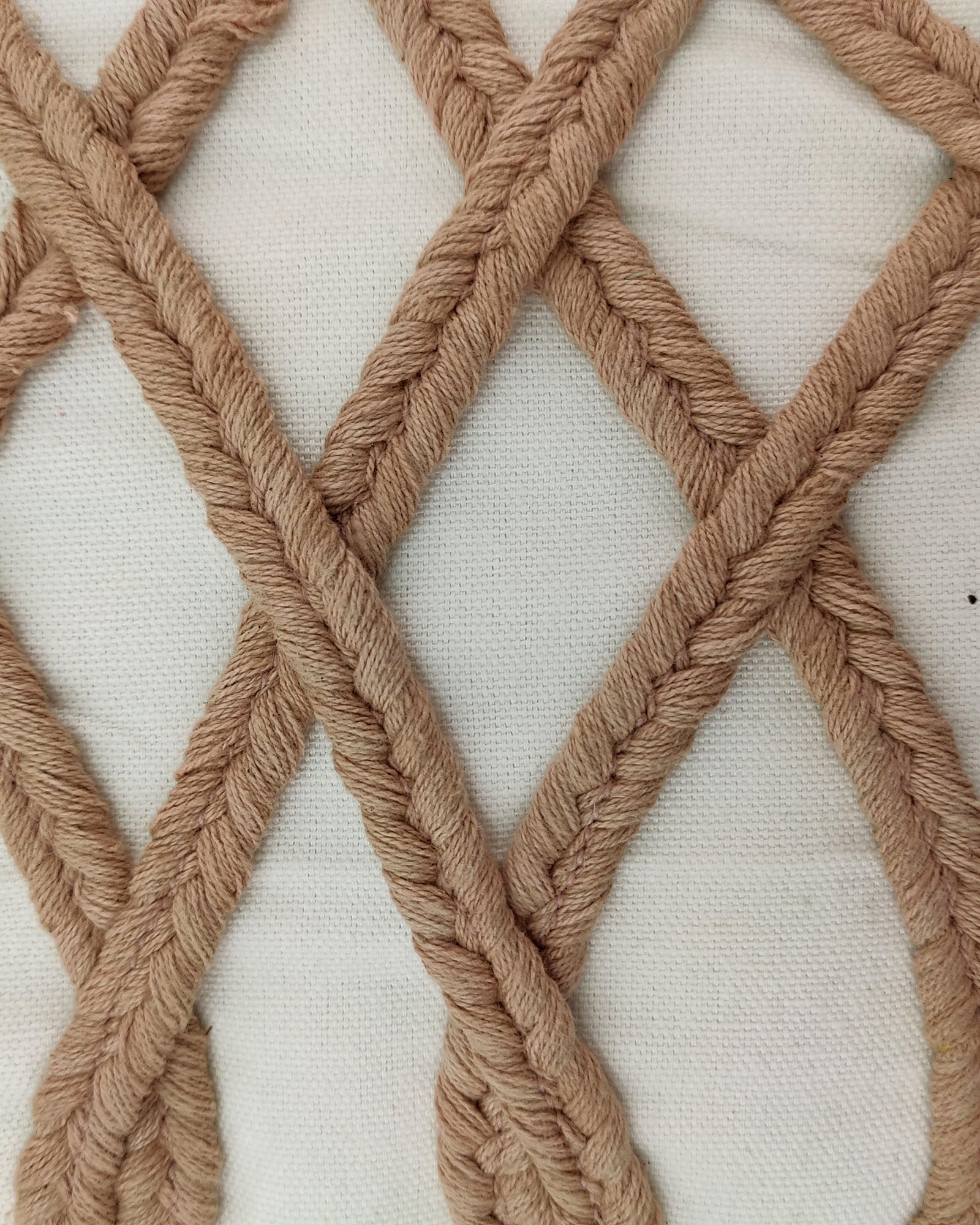 Close-up of Embroidery Cushion With Tassel CS-159 by RAMSHA HOME featuring beige braided yarn in a crisscross lattice on white cotton. The texture of the decorative cushion and yarn is clearly visible.