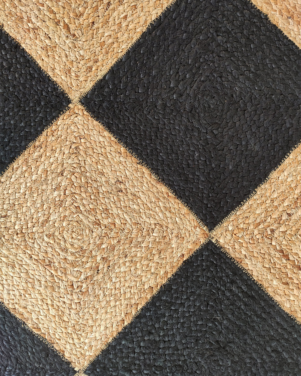 Close-up of the Luxurious Handmade Natural & Black Color Jute Braided Rug with Tassel (BR 030) by RAMSHA HOME, showing its rectangular shape, diamond pattern, and visible braided jute texture.