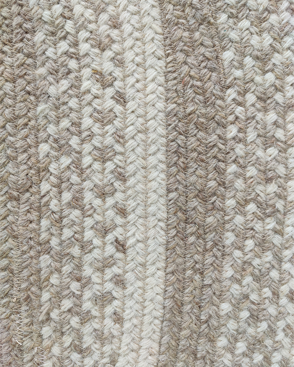 Close-up of the RAMSHA HOME Luxurious Handmade Multi Color Wool Floor Braided Rug - BR 044, showcasing a wool blend in beige, cream, and light brown tones with a rustic, oval design and textured woven pattern.