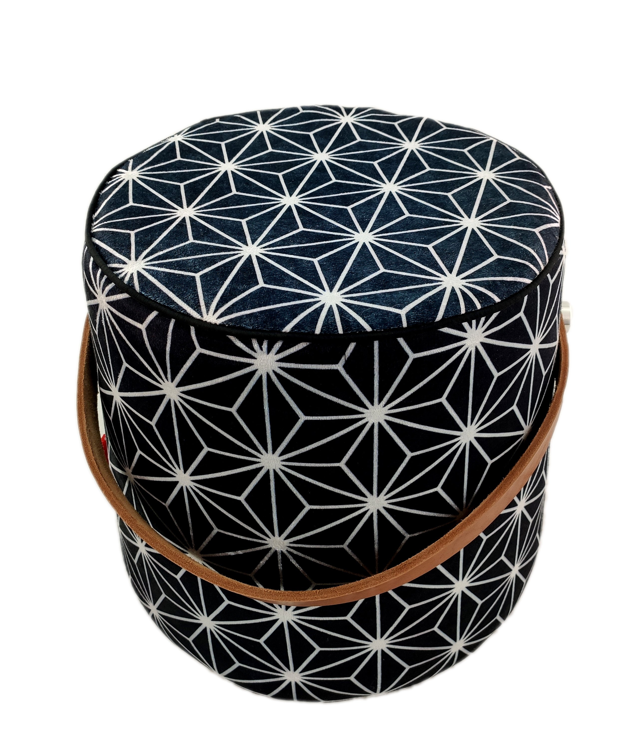 The RAMSHA HOME Printed Pedestal Pouf With Leather Handle PF-027 features a round, black and white geometric star pattern and brown leather handle—ideal for stylish home decor, shown on a white background.