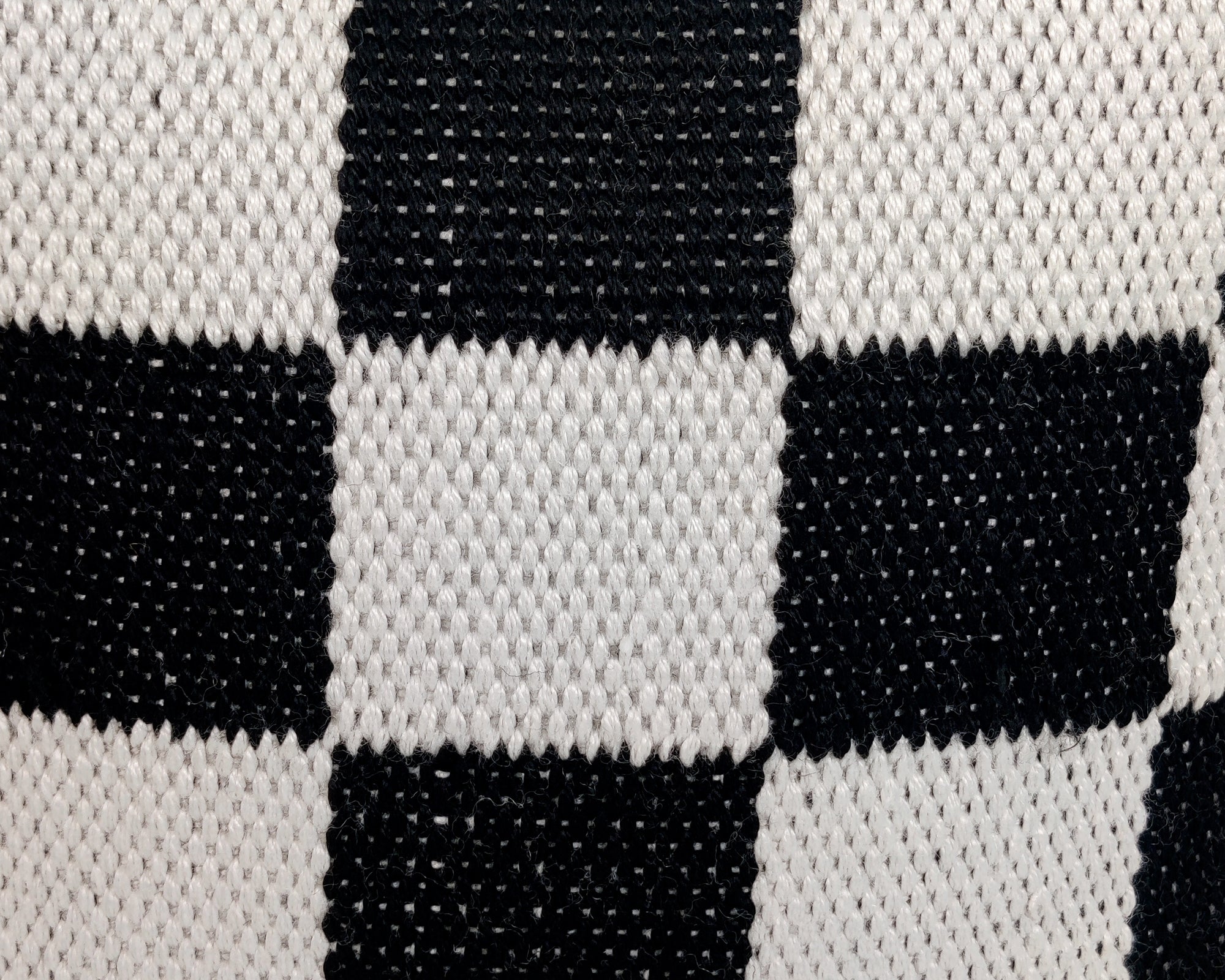 Close-up of the RAMSHA HOME White And Black Polyester Pouf PF-111, highlighting its textured checkerboard weave—an ideal modern accent for your home's seating area.