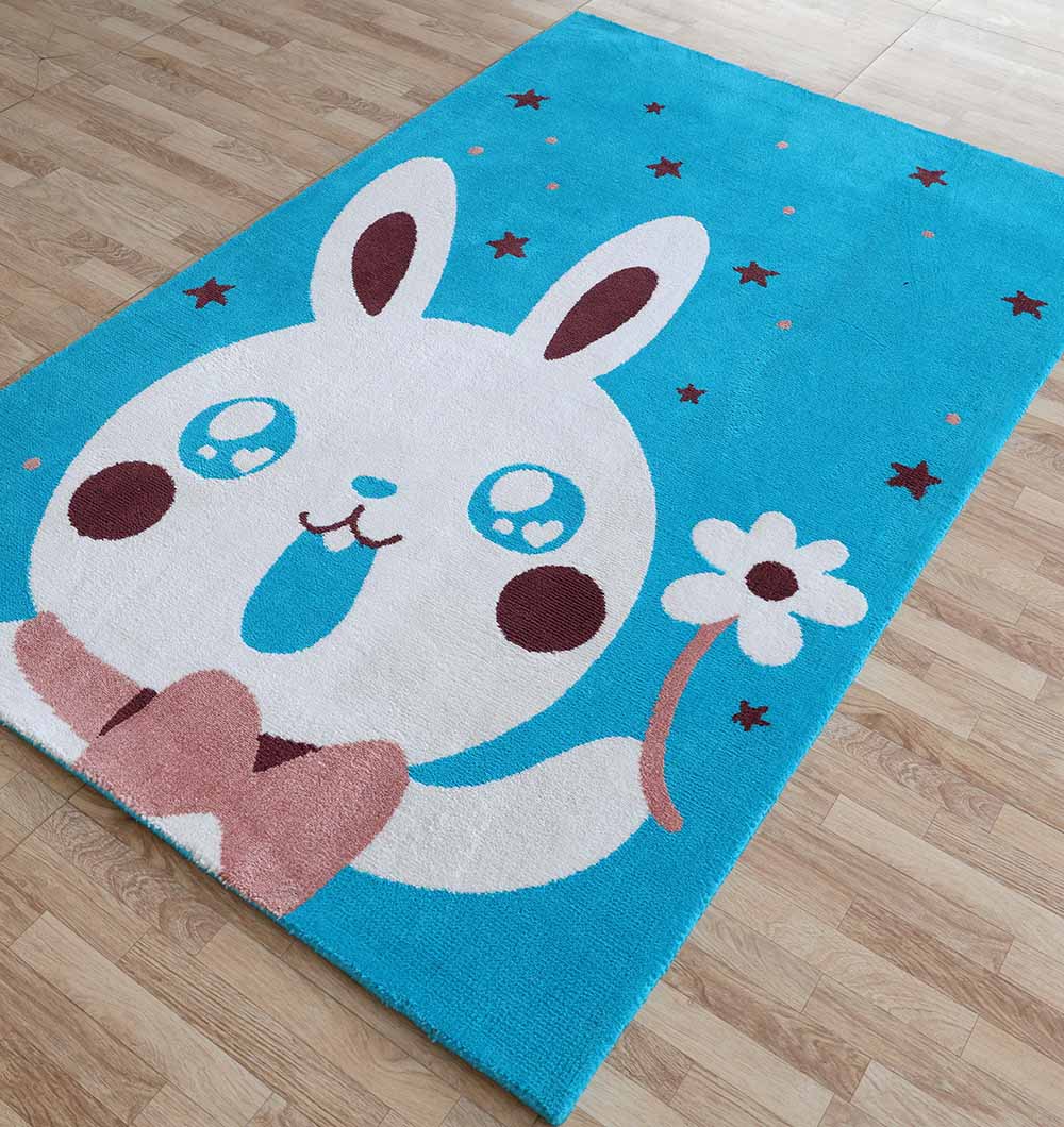 The RAMSHA HOME Multi Color Kids Area Carpet - KD 011 (120x180 cm) is a durable polyester rug featuring a cute white cartoon bunny with a pink bowtie and flower among stars, perfect for brightening light wood floors in any kid's room.
