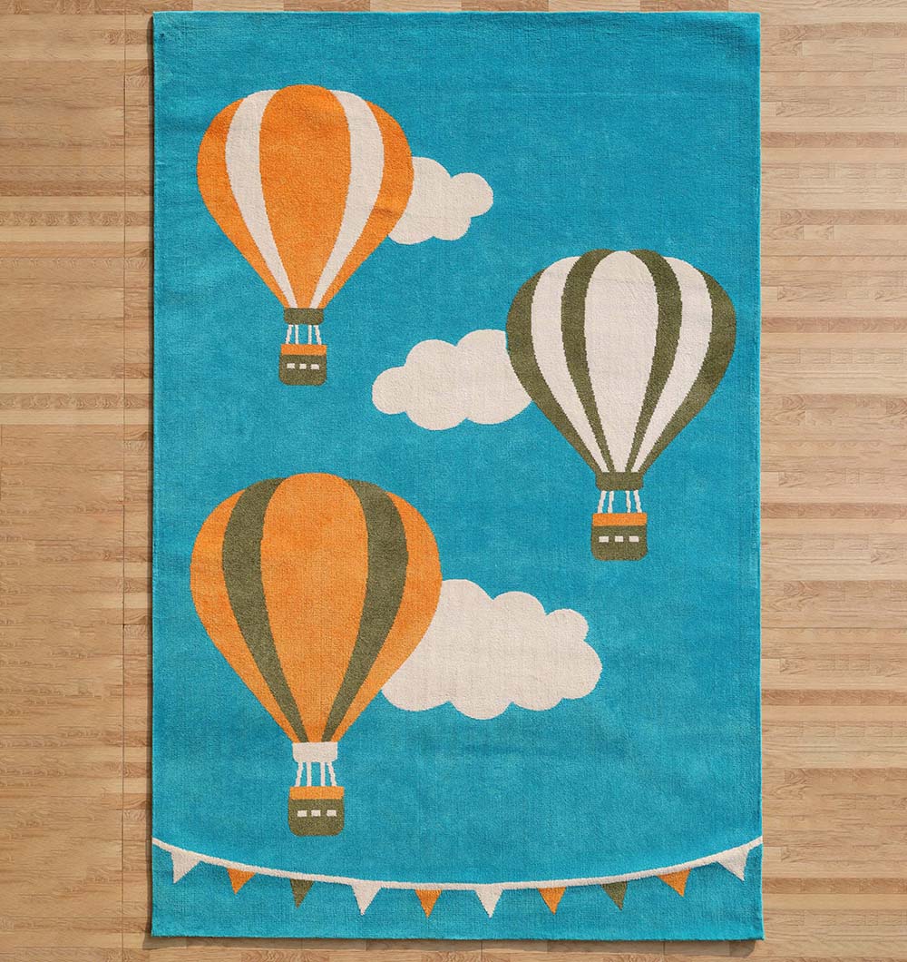 The RAMSHA HOME Modern Kids Area Rug - KD 012 (120x180 cm) features a sky blue design with three hot air balloons—two orange, one gray—white clouds, and a string of triangular flags, shown on a wood floor.