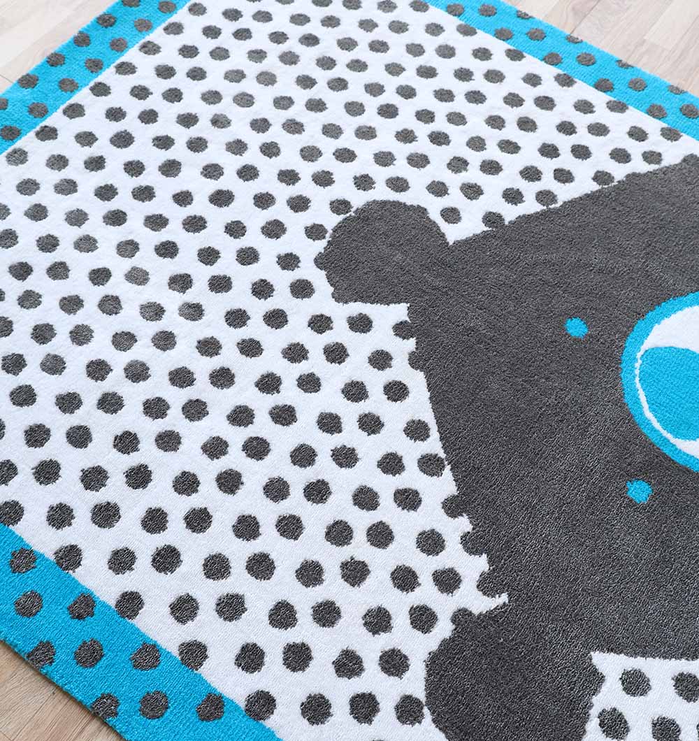 A close-up of the RAMSHA HOME Kids Polka Dot Grey & White Rug with Blue Border (KD 013, 120x180 cm) shows black polka dots on white, a blue border, and part of a black-and-blue rocket—perfect for any child's room.