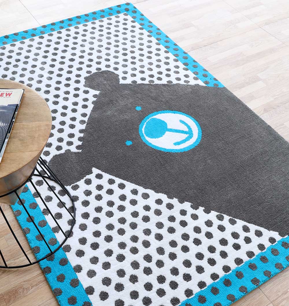 The RAMSHA HOME Kids Polka Dot Grey & White Rug with Blue Border – KD 013 (120x180 cm) features a cartoon bear face, gray polka dots, and a blue border—perfect for kids’ rooms.