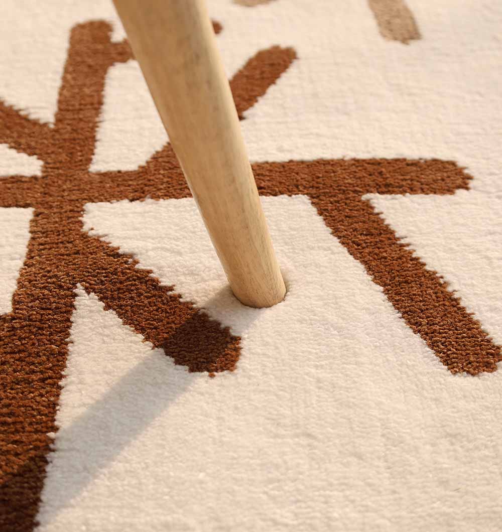 A wooden table leg stands on the RAMSHA HOME Kids Bear Face Beige & Brown Rug – KD 014, casting a shadow over its textured cream and brown surface.