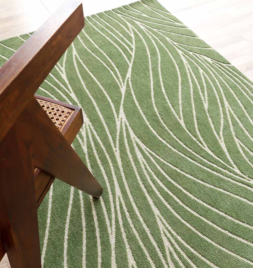 The RAMSHA HOME Leaf Vein Line Pattern Green & Ivory Rug – KD 015 lies on a light wood floor, with the corner of a wooden chair featuring a woven cane seat partially visible on the left side.