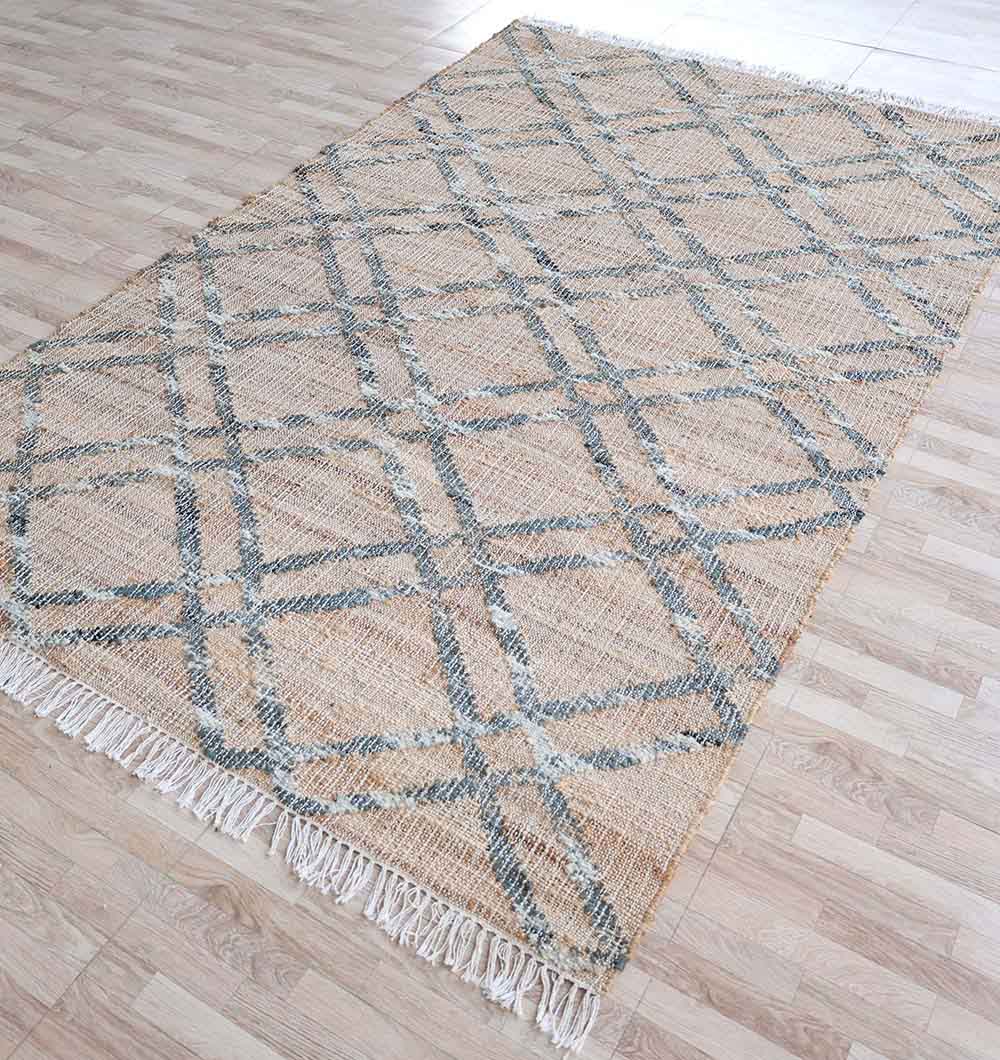 The RAMSHA HOME Fringes Jute & Cotton Kilim Flatweave Carpet - KLM 002 (170x240cm) features a beige base with dark gray and blue geometric patterns plus white fringes, shown on a light wood floor.