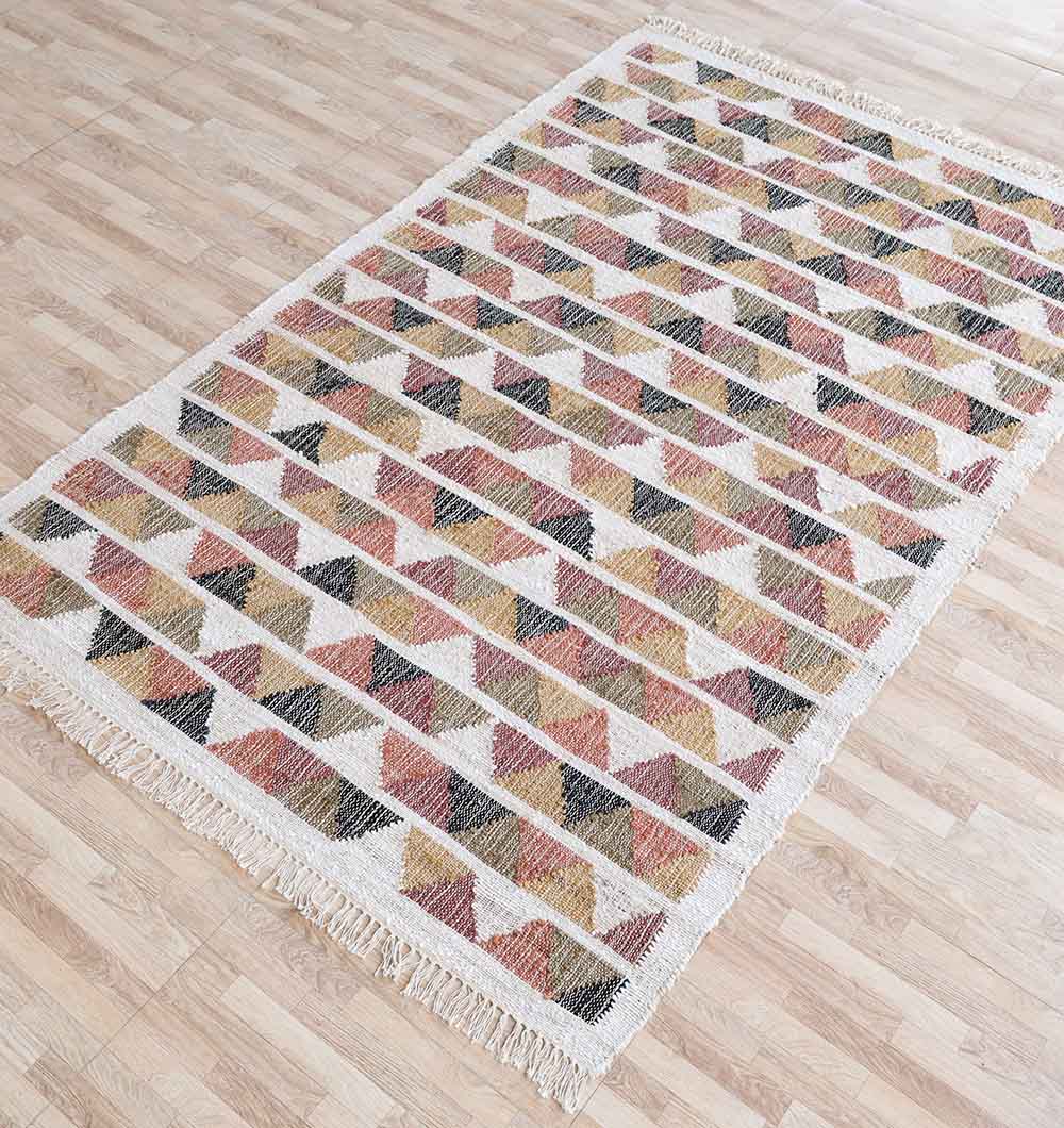 The RAMSHA HOME Geometric Jute Tribal Kilim Rug – KLM 003 (170x240cm) features multicolored triangles in brown, black, yellow, and red with fringed edges and a natural texture, adding style to any light wood floor.
