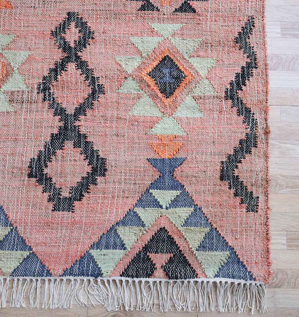 The RAMSHA HOME Handwoven Jute Flatweave Pink Kilim Rug – KLM 005 (170x240cm) features black, orange, blue, and cream geometric patterns with fringed edges—a vibrant pink tribal rug for any modern space.