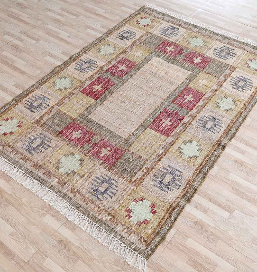 The RAMSHA HOME Symmetrical Bordered Traditional Kilim Rug - KLM 007 (170x240cm) features a geometric bohemian design in muted reds, beige, green, and gray with fringe edges, shown on a light wood floor.