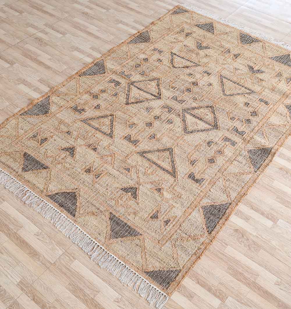 The RAMSHA HOME Minimalist Neutral Jute Tribal Kilim Rug - KLM 008 (170x240cm) showcases earthy-toned triangles and diamonds with short white fringes, adding warmth to a light wood floor.