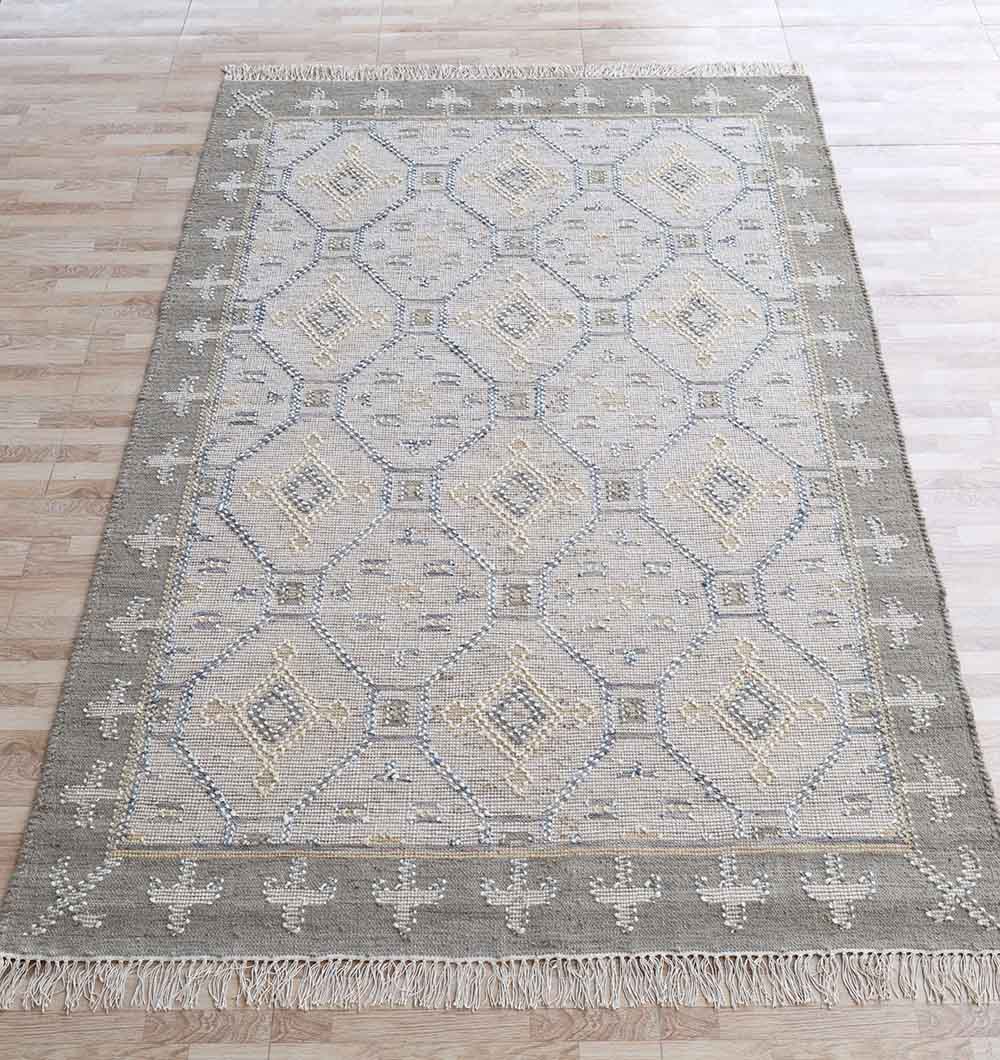 The RAMSHA HOME Neutral Diamond Geometric Flatweave Kilim Rug - KLM 009 (170x240cm) features a grey, diamond-patterned design with fringed edges and a decorative border, shown on a light wood floor.