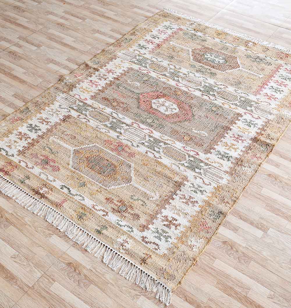 The RAMSHA HOME Jute Cotton Blend Turkish Styled Kilim Rug (KLM 011) features geometric patterns in beige, rust, green, and cream with fringed edges and a natural texture, shown on a light wood floor.