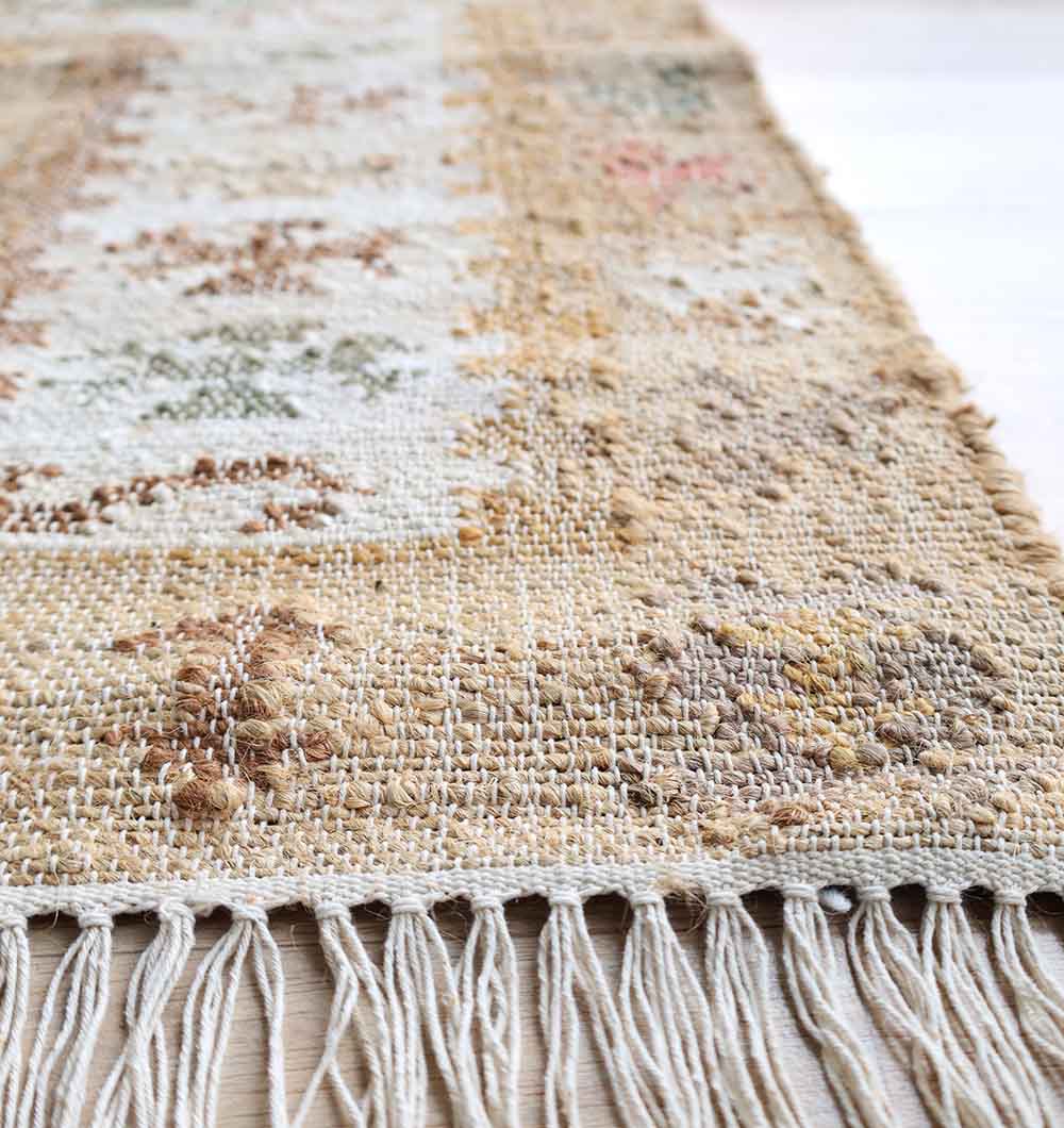 A close-up of the edge of RAMSHA HOME’s Jute Cotton Blend Turkish Styled Kilim Rug (KLM 011), featuring tasseled fringe, natural texture, and intricate patterns in muted brown and cream tones.