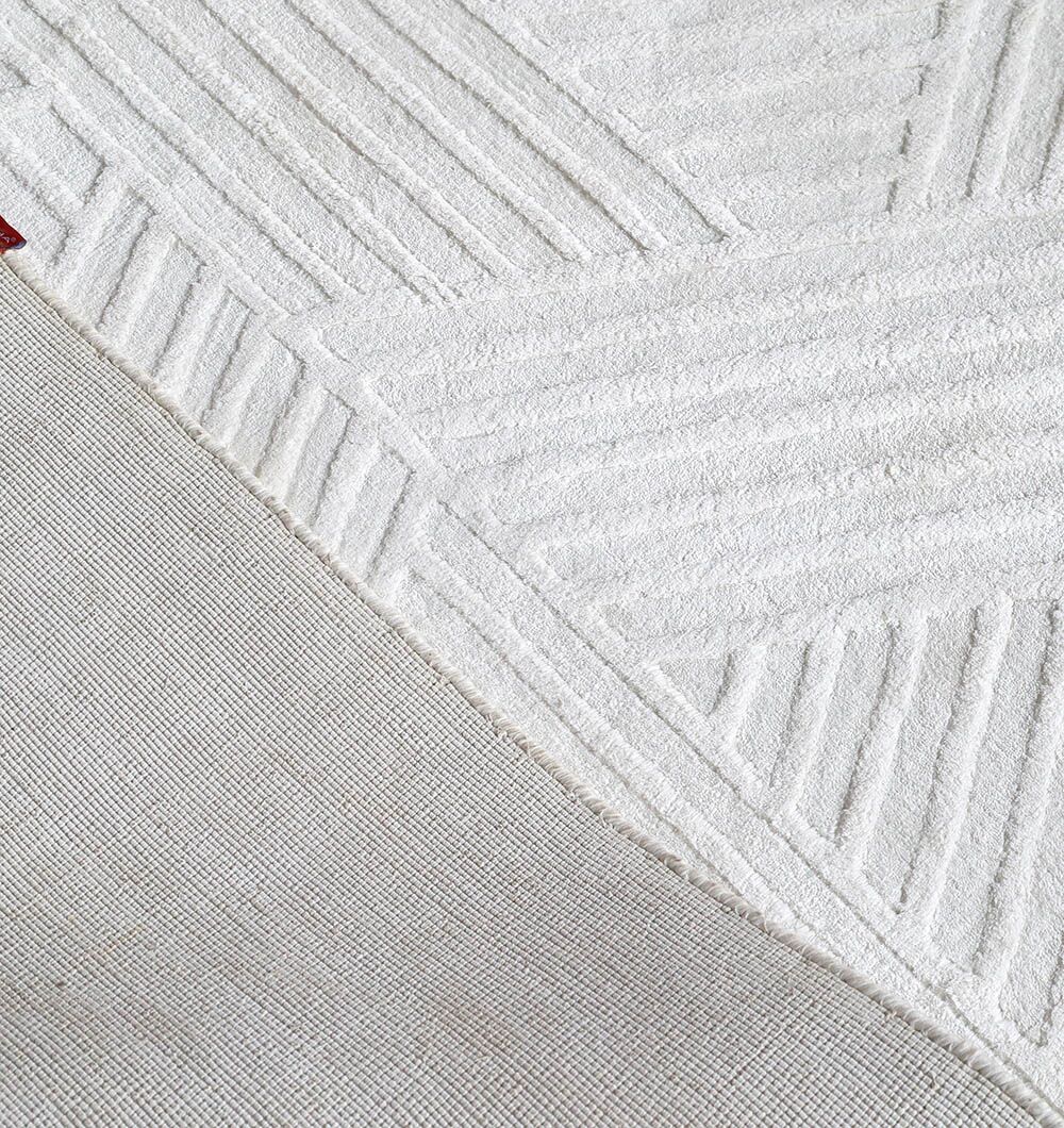 A close-up of the RAMSHA HOME Handmade Natural Color Area Rug - LKH 015 shows off-white geometric, raised patterns with a smooth, flat diagonal section.