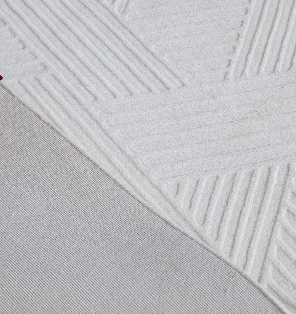 A close-up of the RAMSHA HOME Geometric Woven Natural Color Handmade Area Rug (LKH-016) highlights its textured chevron pattern beside a smoother, darker fabric.