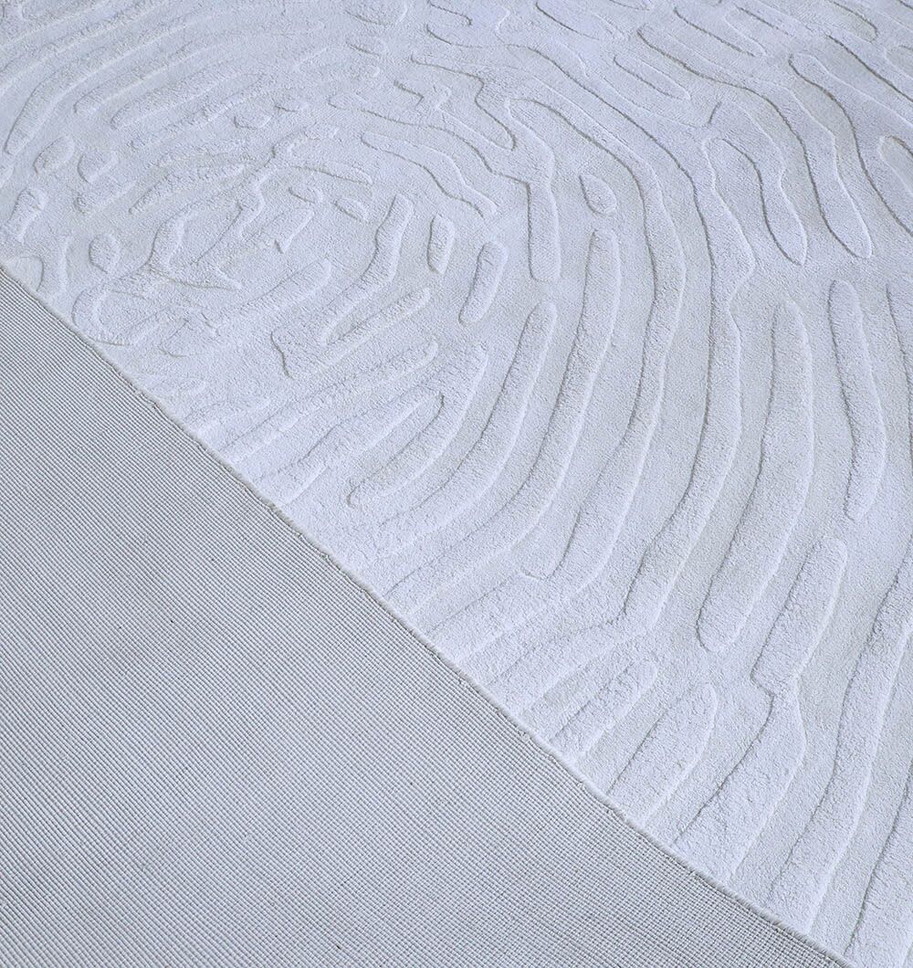 A close-up of the RAMSHA HOME Decorative Handmade Area Rug (LKH-017) shows its textured light gray surface with raised abstract patterns and a smooth, plain section diagonally intersecting at the bottom left.