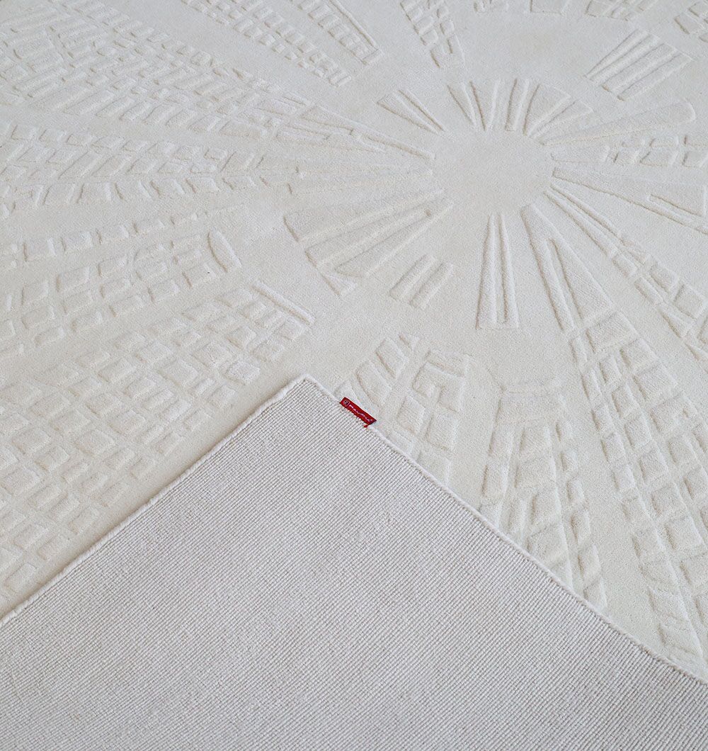The RAMSHA HOME Handmade Decorative Area Rug - LKH-019 (200x300 cm) is a cream-colored wool piece with a textured geometric sunburst design, an ivory solid backing shown at the folded corner, and a small red tag along the edge.