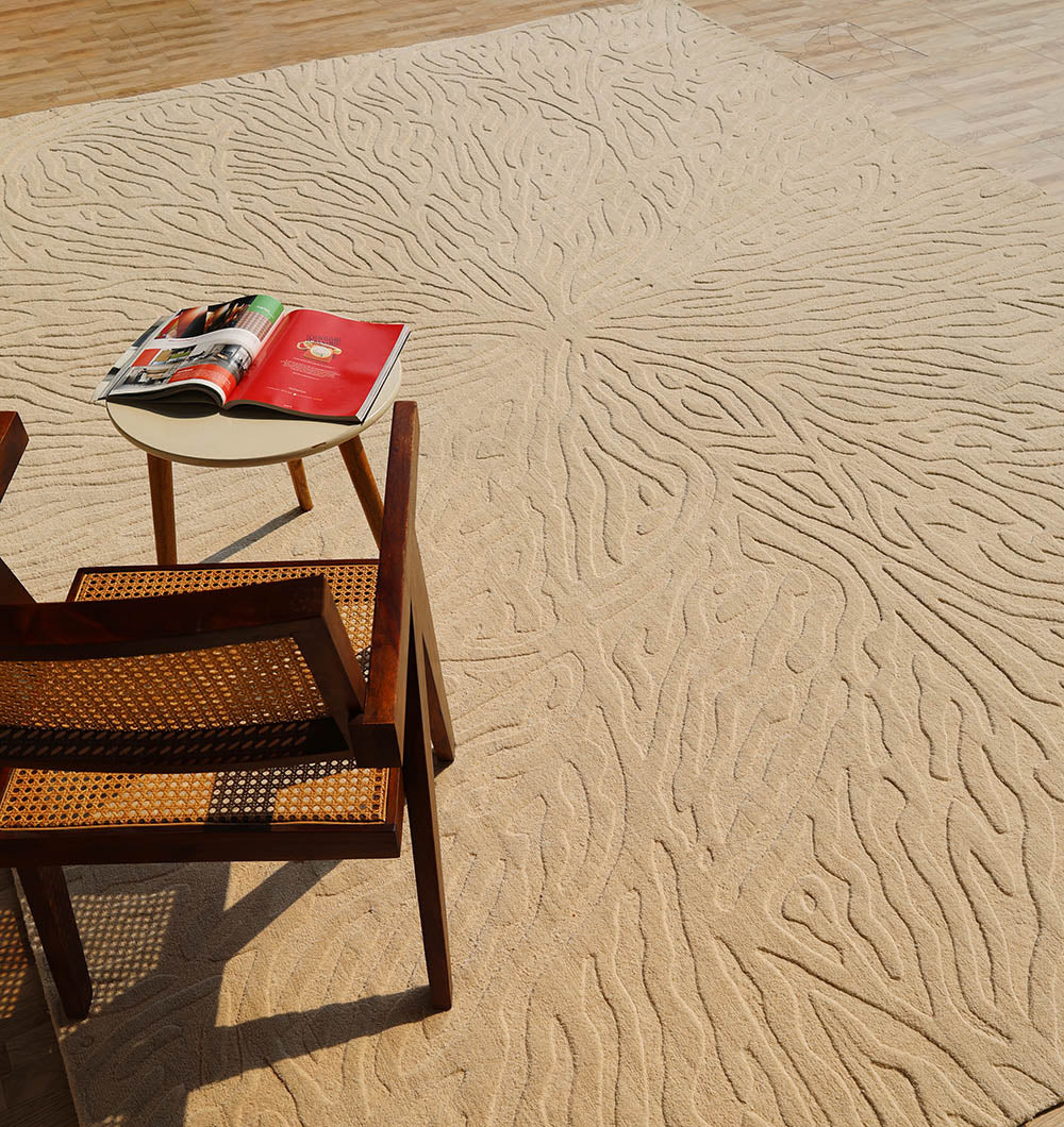 A wooden chair and small white table with an open magazine rest on the RAMSHA HOME Handmade Beige Rug with Organic Tree-Inspired Pattern (LKH-025), set atop a light wood floor.