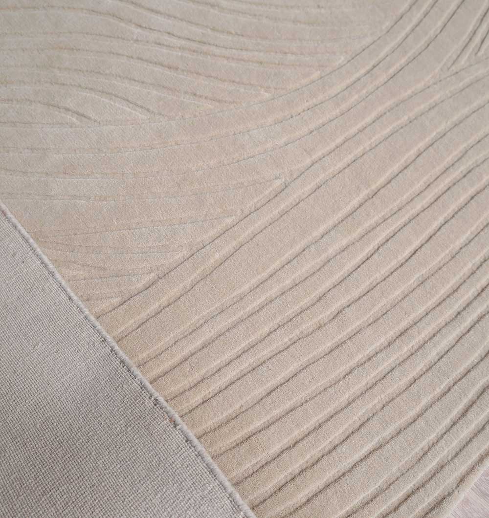 A close-up of the RAMSHA HOME Decorative Rectangle Handmade Beige Area Rug (300x400 cm, LKH-033), showing wavy, raised lines across its textured surface and a seam forming a triangular section in the lower left corner.