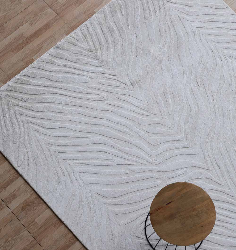The RAMSHA HOME Rectangle Handmade Natural Color 200x300 cm rug (LKH-035) adds modern style with its subtle wavy pattern on a wood floor, complemented by a round wooden table in the lower right corner.