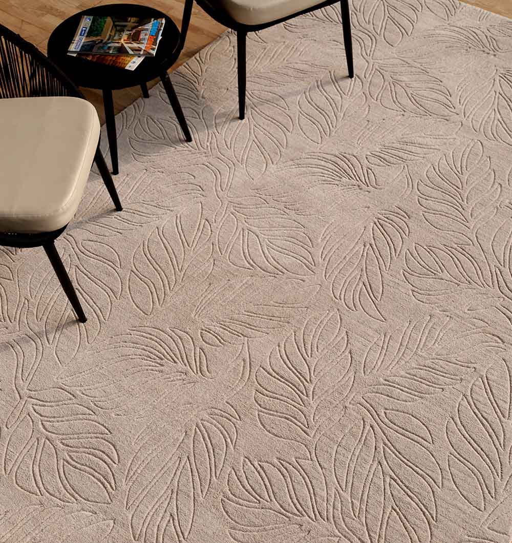 A RAMSHA HOME Decorative Rectangle Handmade Grey 200x300 cm Area Rug (LKH-039) is laid on a wooden floor, topped with two modern chairs featuring black legs and cream cushions, plus a small round black side table with magazines.