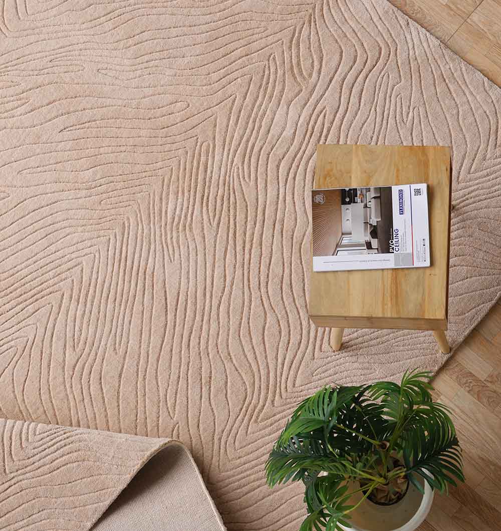 The RAMSHA HOME Rectangle Handmade Beige 200x300 cm Area Rug (LKH-040) features wavy patterns and is placed on a wooden floor, accompanied by a small table with an open magazine and a green potted plant nearby.