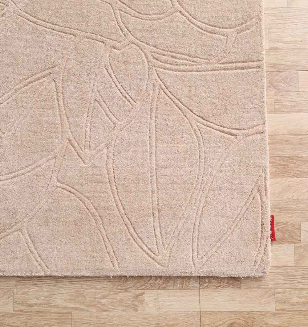 The RAMSHA HOME Rectangle Handmade Beige Color 200x300 cm Area Rug (LKH-041) features a subtle raised leaf pattern and is displayed on a light wood floor, with a small red tag on the lower right corner adding distinctive detail.