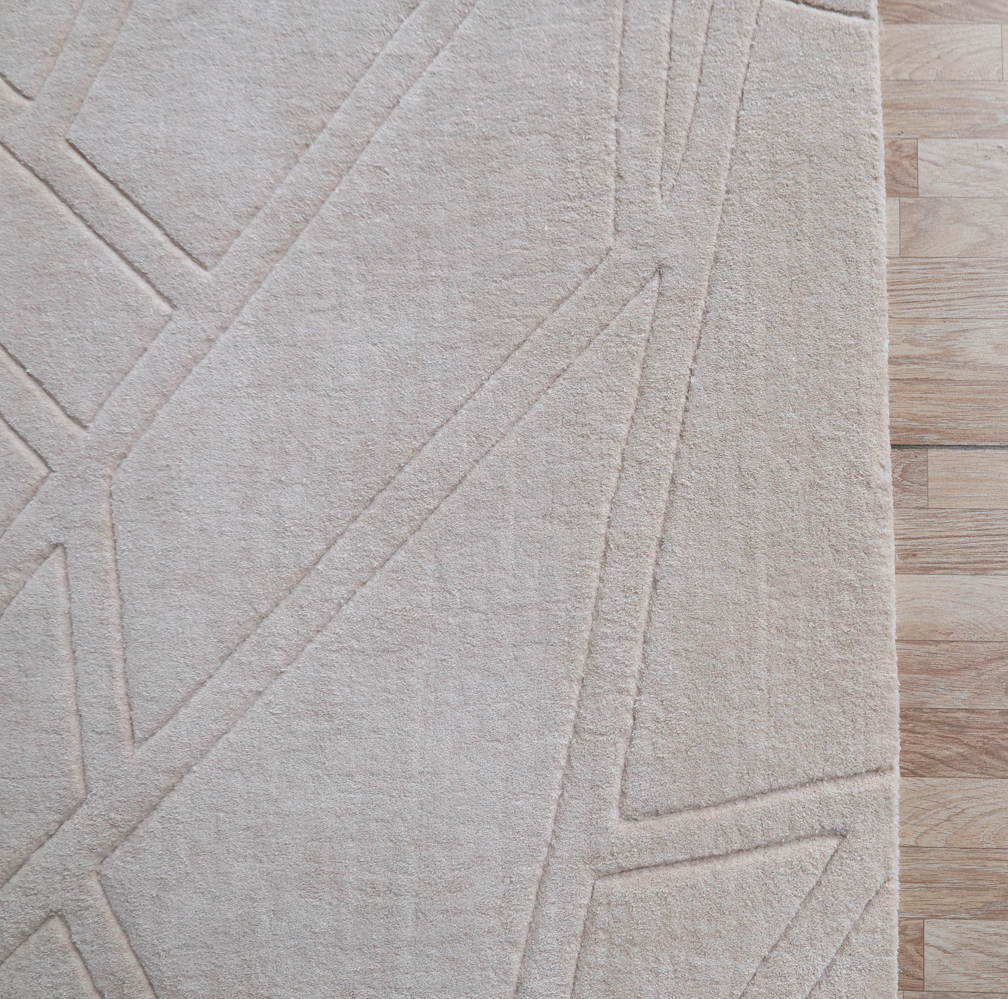 A close-up of the RAMSHA HOME Rectangle Home Decor Cream Color Handmade Area Rug 300x400 cm (LKH-045) featuring abstract, raised line patterns beside a light wood floor.