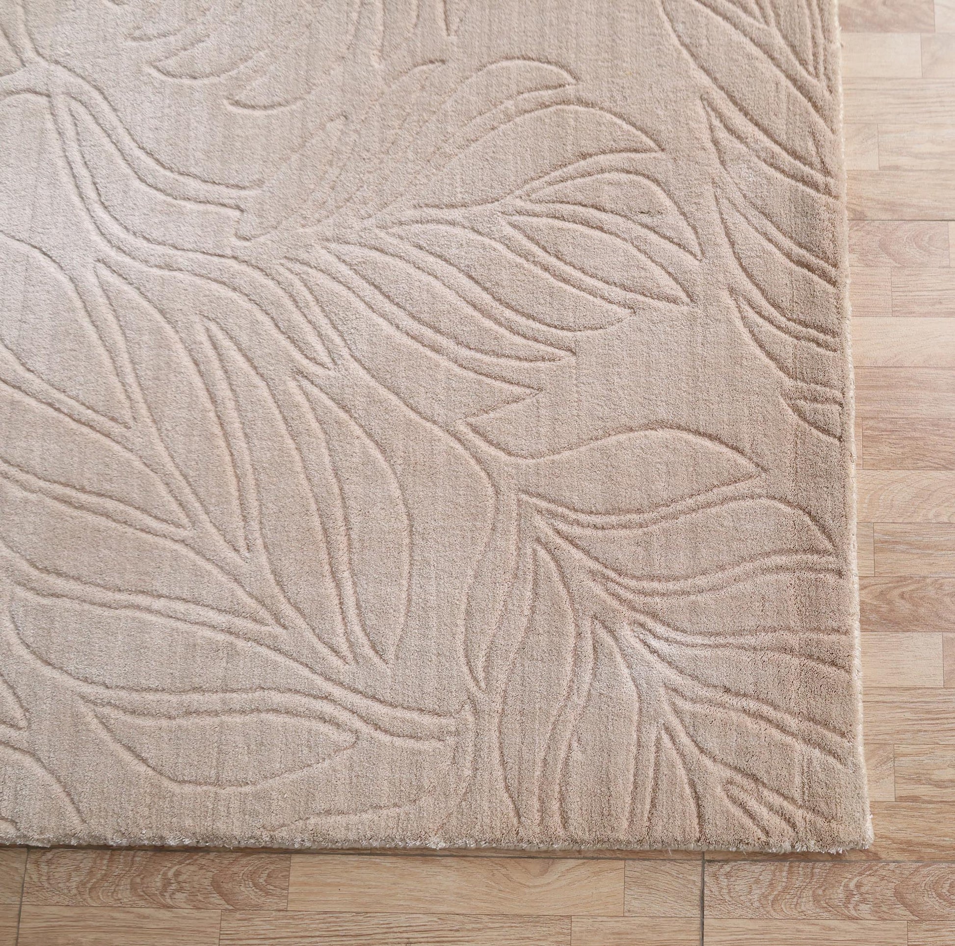 The RAMSHA HOME Nature Leaf Handmade Contemporary Rug 250x350 cm (LKH-048) in neutral ivory, featuring a raised botanical leaf pattern, is displayed on a light wooden floor from an overhead view.