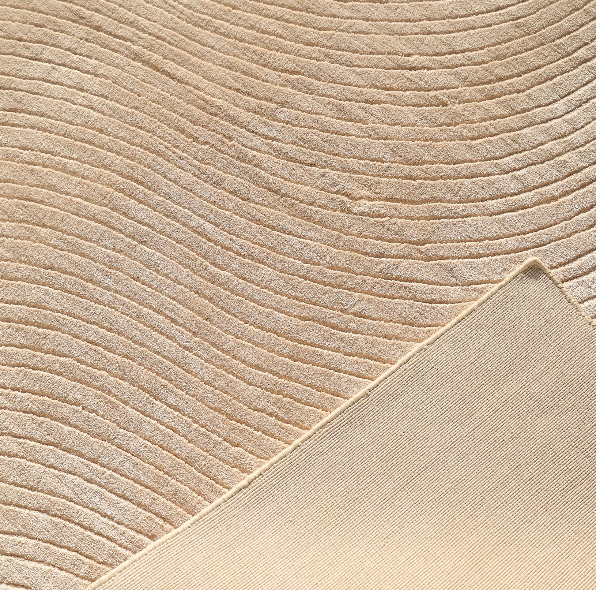 Close-up of the RAMSHA HOME Handmade Beige Wave Modern Abstract High-Low Area Rug (250x350 cm, LKH-049), showing its textured wavy pattern and a flipped corner revealing the plain underside for a subtle, elegant touch.
