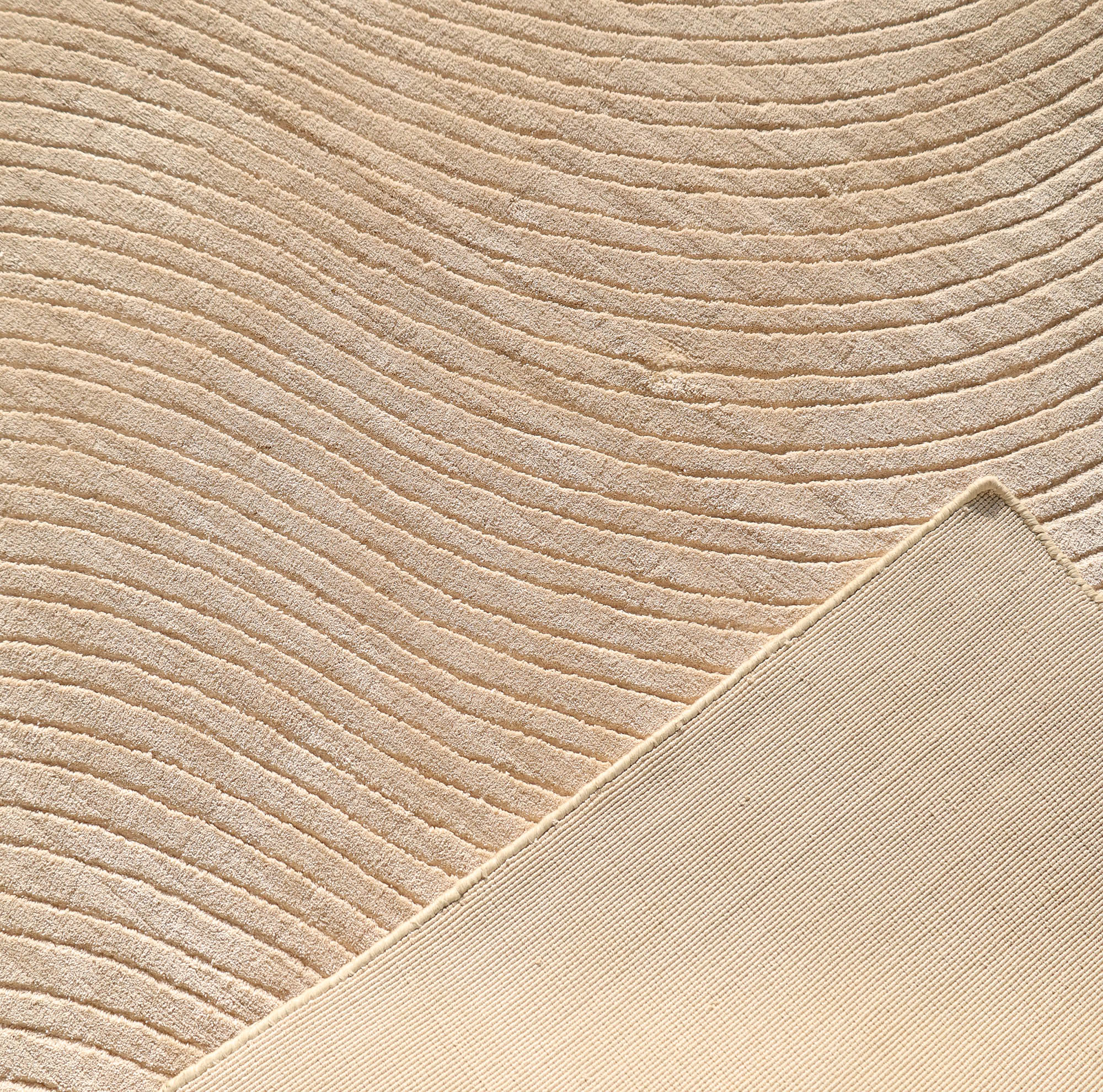 Close-up of the RAMSHA HOME Handmade Beige Wave Modern Abstract High-Low Area Rug (250x350 cm, LKH-049), showing its textured wavy pattern and a flipped corner revealing the plain underside for a subtle, elegant touch.